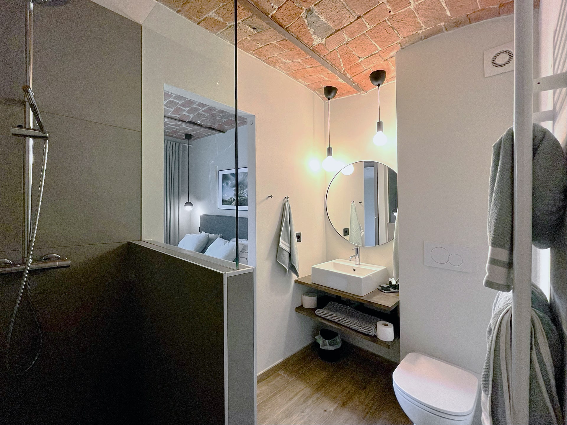 Ensuite bathroom with shower, round mirror, and warm ceiling detail